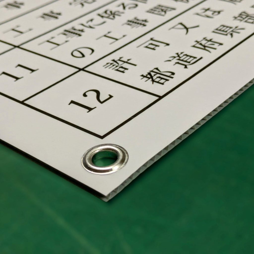 取り付け用に四隅ハトメ加工したダンプラ看板